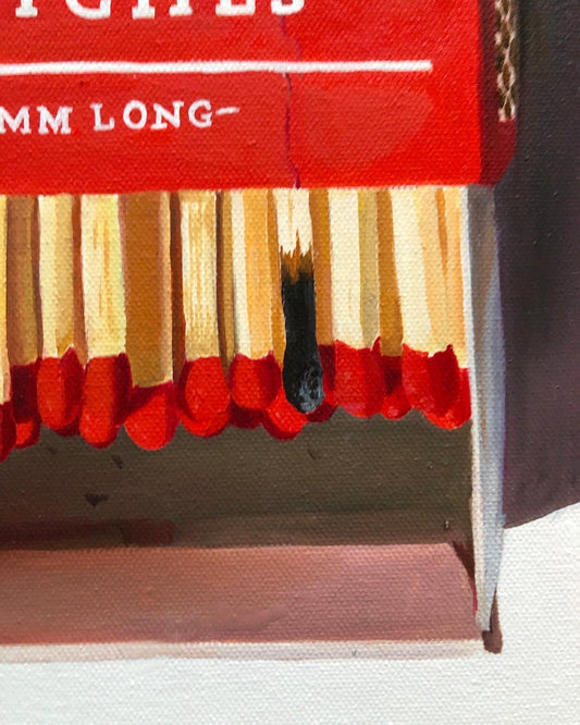 Realistic pop art painting of red-tipped matches in a matchbook with one burnt match