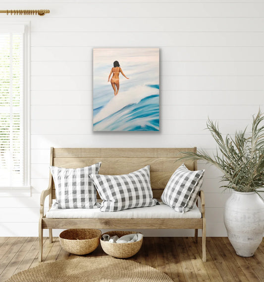 Coastal living room with a pop art surfing painting, wooden bench, checkered pillows, and plants