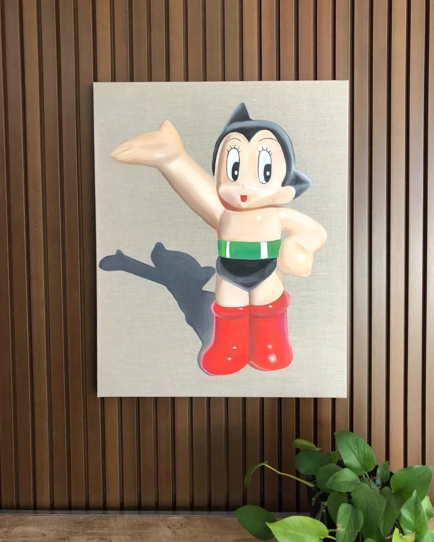 Pop art painting of a retro cartoon figure with red boots on linen, wall-mounted above a plant