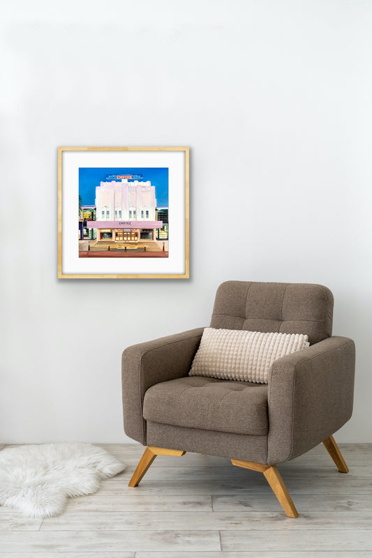 Framed pop art Empire Theatre print on white wall above modern armchair, minimalist decor
