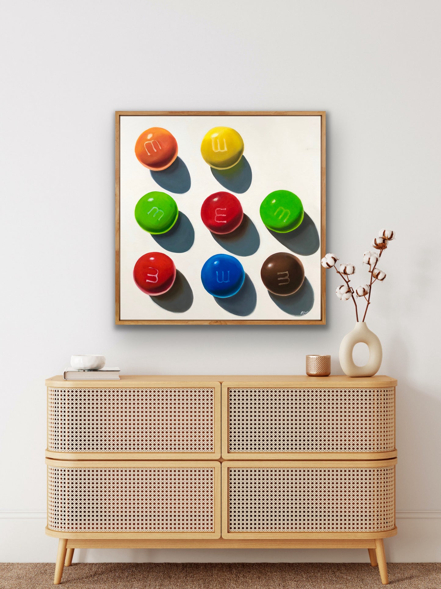 Framed pop art painting of colorful candy circles in a grid above a modern sideboard.