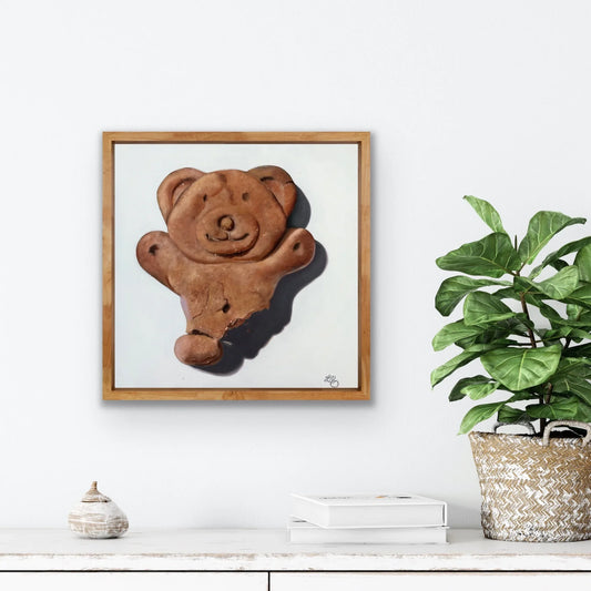 Framed pop art painting of a bitten chocolate teddy bear biscuit on a white wall